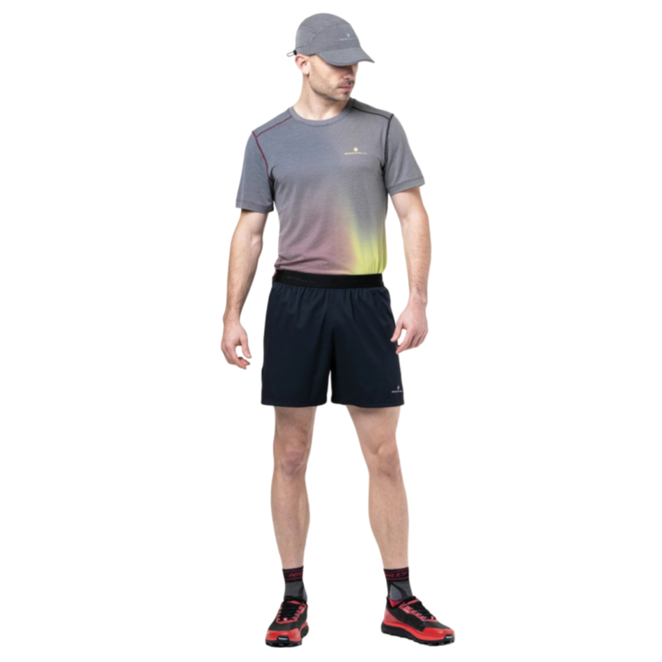 Up & Running model wearing Ronhill black 5-inch running shorts with a grey patterned technical t-shirt and cap