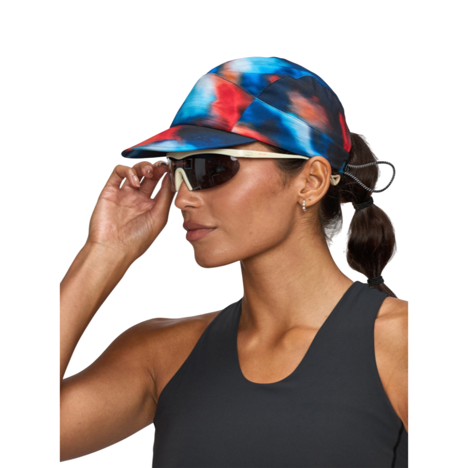 Up & Running Janji AFO Hyperlight running cap in blue, red, and black abstract print with adjustable bungee strap.