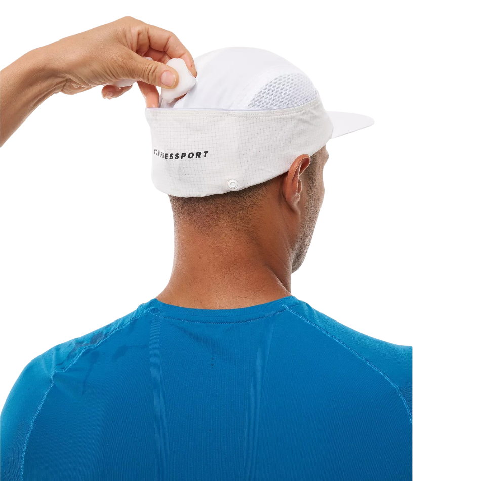 Up & Running Compressport white racing cap with rear ice pocket being filled by a hand for cooling during a run
