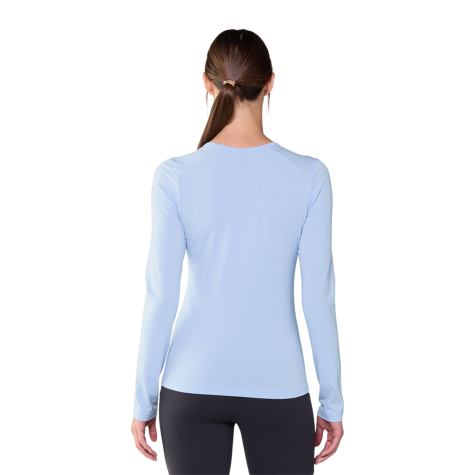 Back view of a woman wearing a light blue Janji Circa Daily long sleeve performance shirt by Up & Running