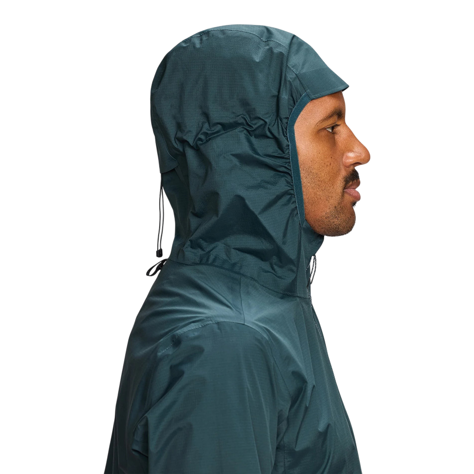 Up & Running Janji Men's Rainrunner Pack Jacket in Atlantis teal, featuring an adjustable hood and ripstop fabric.