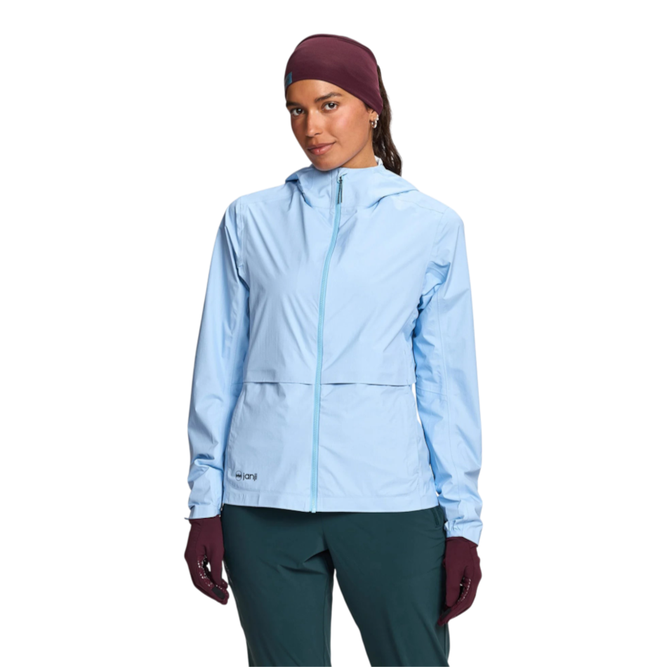 Up & Running Janji Women's Rainrunner Pack Jacket in light blue, featuring a hood and zip front for running.