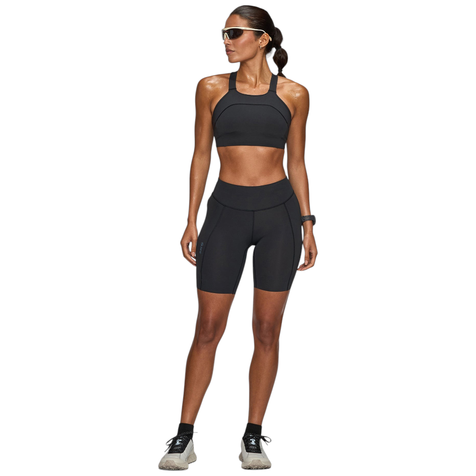 Up & Running model wearing Janji women's 7-inch Pace running shorts in midnight black with a matching sports bra