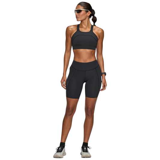 Up & Running model wearing Janji women's 7-inch Pace running shorts in midnight black with a matching sports bra